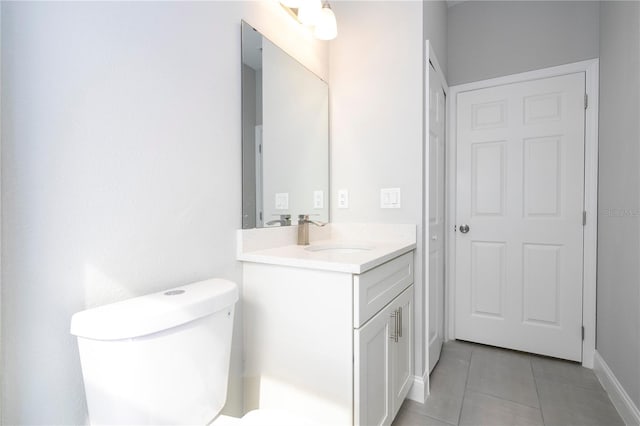 bathroom with toilet, vanity, and tile patterned floors