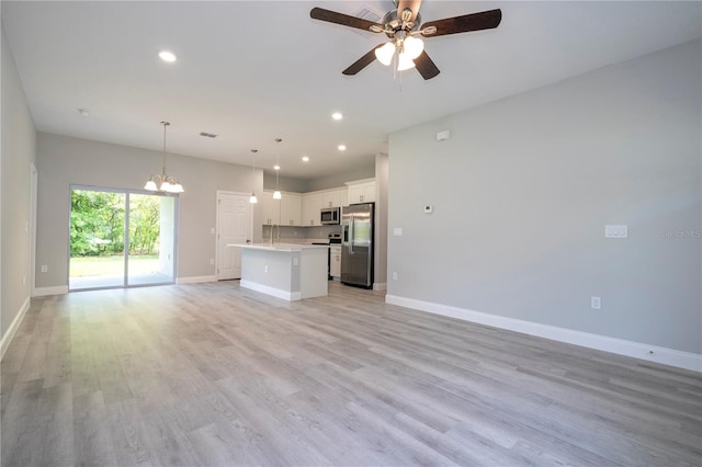 unfurnished living room featuring light wood-type flooring and ceiling fan with notable chandelier