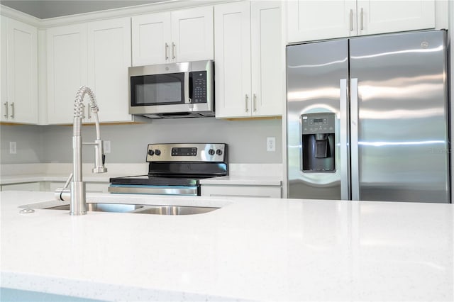 kitchen with white cabinetry, appliances with stainless steel finishes, and light stone counters