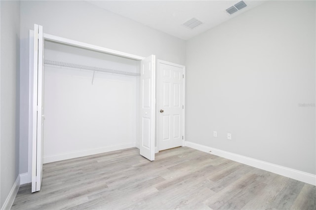 unfurnished bedroom with light wood-type flooring and a closet