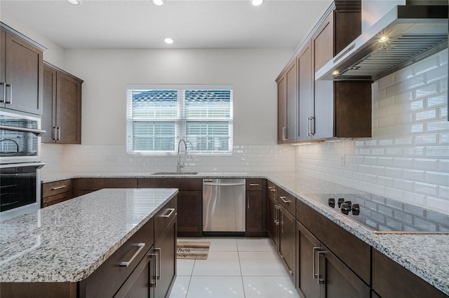 kitchen with light tile flooring, tasteful backsplash, light stone counters, stainless steel appliances, and wall chimney exhaust hood