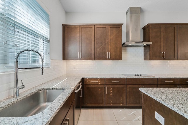 kitchen with sink, wall chimney range hood, light stone counters, and light tile floors