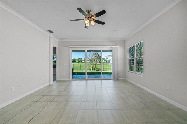 tiled empty room featuring plenty of natural light, ornamental molding, and ceiling fan