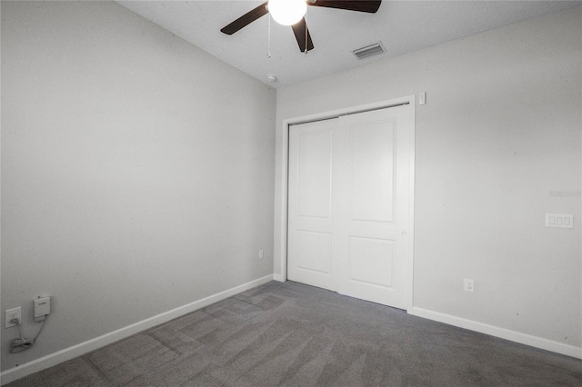 unfurnished bedroom featuring ceiling fan, dark colored carpet, and a closet