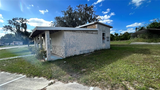 view of home's exterior with a carport and a lawn