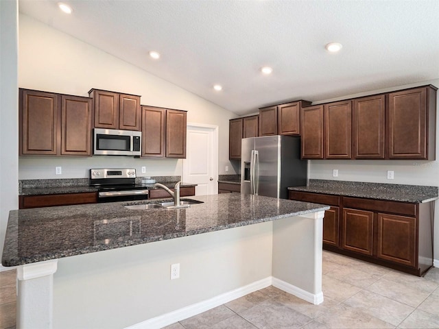 kitchen featuring sink, stainless steel appliances, lofted ceiling, a kitchen island with sink, and dark brown cabinetry