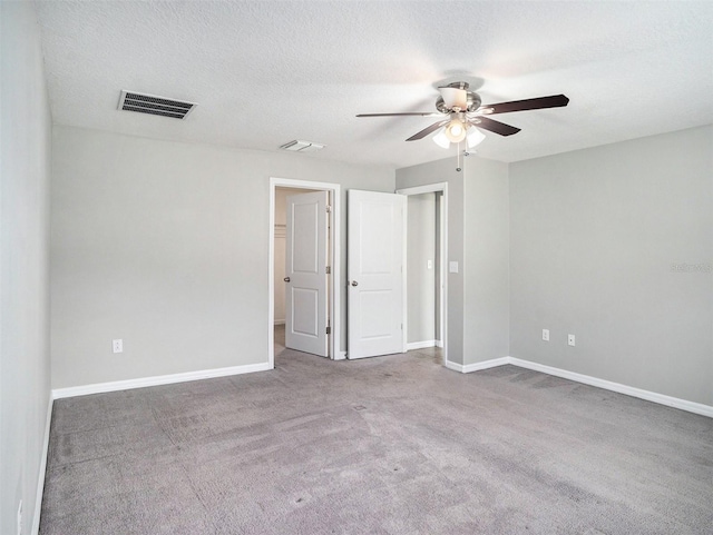 carpeted spare room with ceiling fan and a textured ceiling