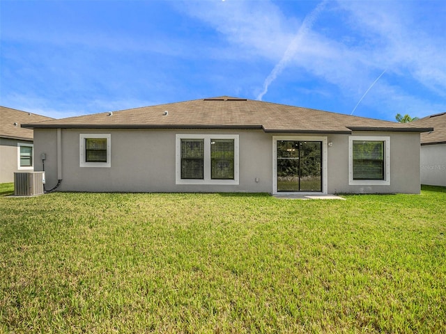 rear view of property featuring central AC and a lawn