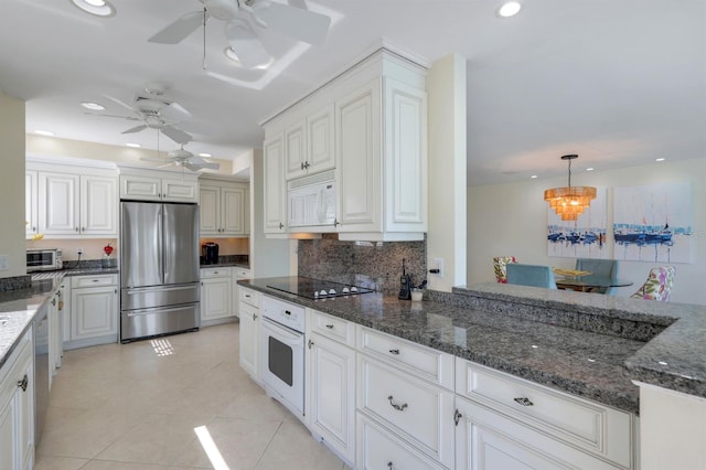 kitchen featuring appliances with stainless steel finishes, ceiling fan, light tile floors, and dark stone countertops