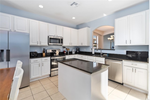 kitchen featuring light tile flooring, appliances with stainless steel finishes, sink, a chandelier, and a kitchen island