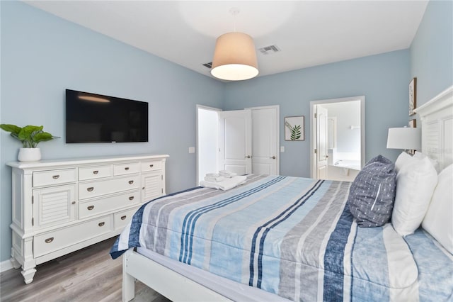 bedroom featuring ensuite bath and hardwood / wood-style floors