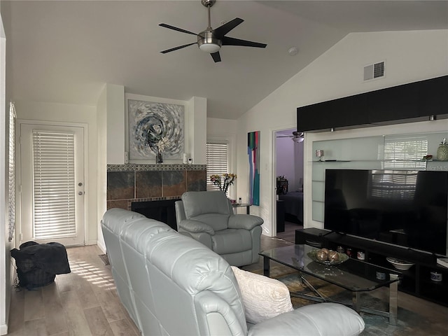 living room with lofted ceiling, ceiling fan, light wood-type flooring, and a fireplace