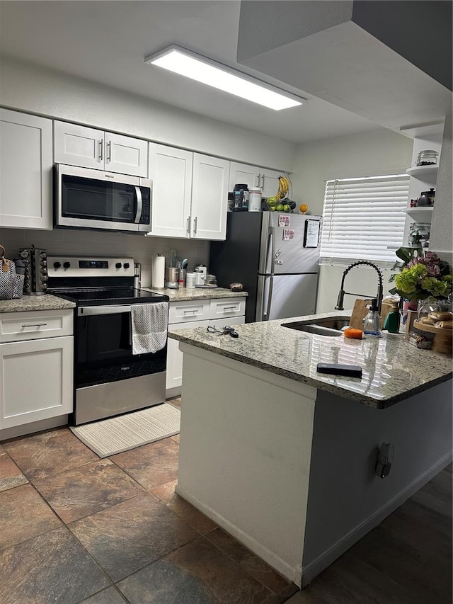 kitchen with white cabinetry, sink, light stone counters, and stainless steel appliances