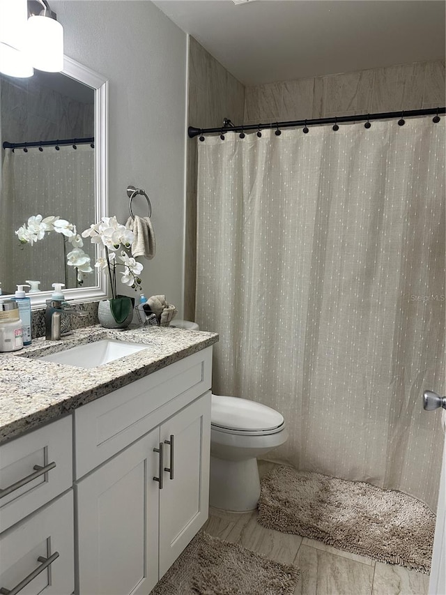 bathroom with tile floors, toilet, and vanity