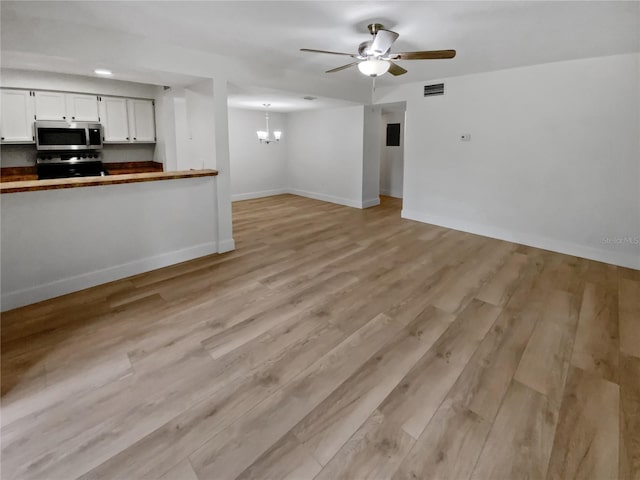 interior space featuring ceiling fan with notable chandelier and light wood-type flooring