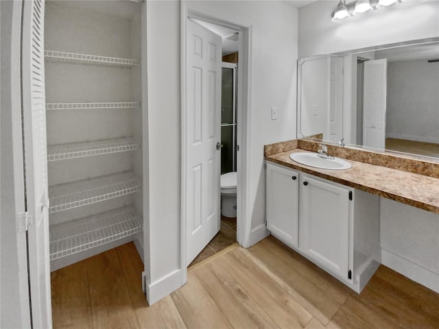 bathroom with toilet, vanity, and wood-type flooring