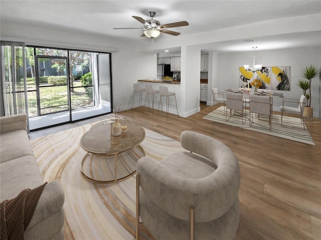 living room with light hardwood / wood-style floors and ceiling fan with notable chandelier