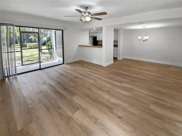 unfurnished living room with hardwood / wood-style flooring and ceiling fan with notable chandelier