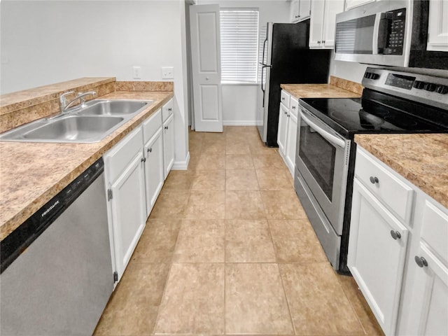 kitchen featuring appliances with stainless steel finishes, sink, white cabinetry, and light tile flooring