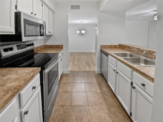 kitchen with appliances with stainless steel finishes, white cabinetry, ceiling fan with notable chandelier, and sink