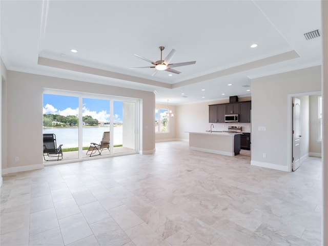 unfurnished living room featuring a raised ceiling, ceiling fan with notable chandelier, and light tile floors