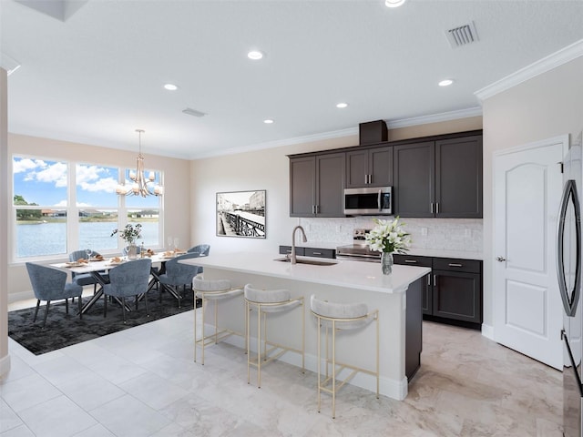 kitchen featuring an inviting chandelier, appliances with stainless steel finishes, an island with sink, light tile floors, and hanging light fixtures