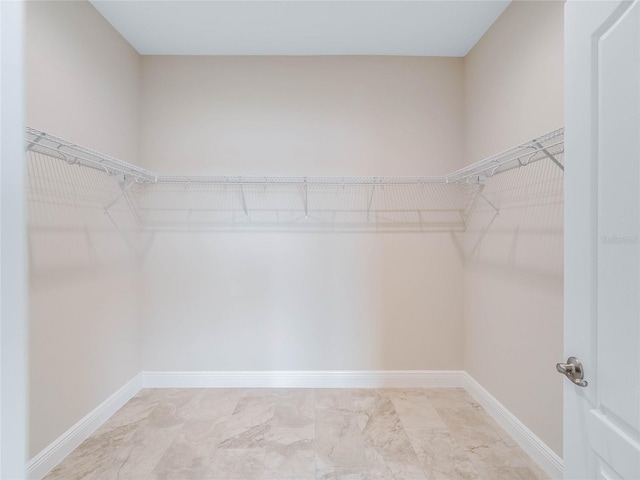 walk in closet with light tile floors