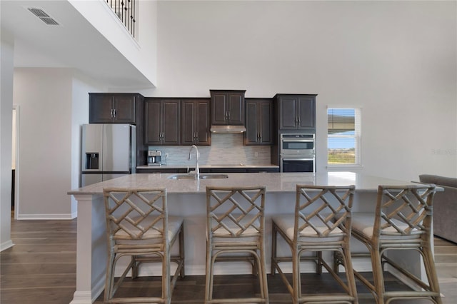 kitchen with stainless steel appliances, a center island with sink, a kitchen bar, and sink