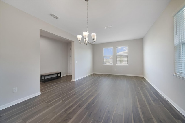 empty room featuring dark hardwood / wood-style flooring and a chandelier