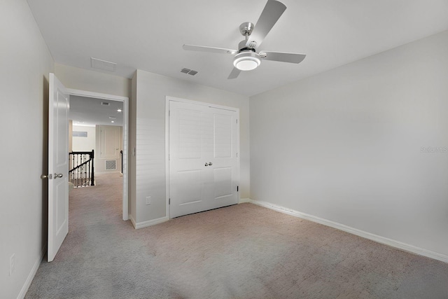 unfurnished bedroom featuring light carpet, a closet, and ceiling fan