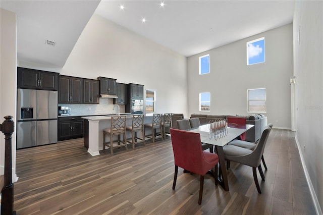 dining room with dark hardwood / wood-style flooring, sink, and high vaulted ceiling