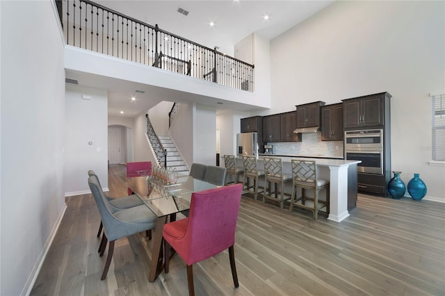 dining space with a towering ceiling and light hardwood / wood-style flooring