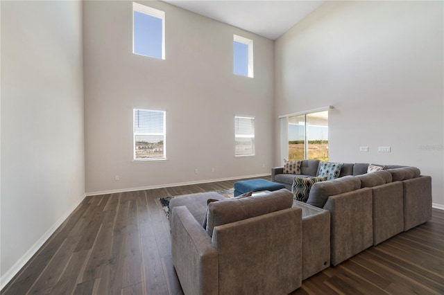 living room featuring a towering ceiling, dark hardwood / wood-style floors, and a healthy amount of sunlight