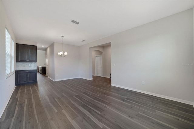 unfurnished living room featuring a notable chandelier and dark wood-type flooring