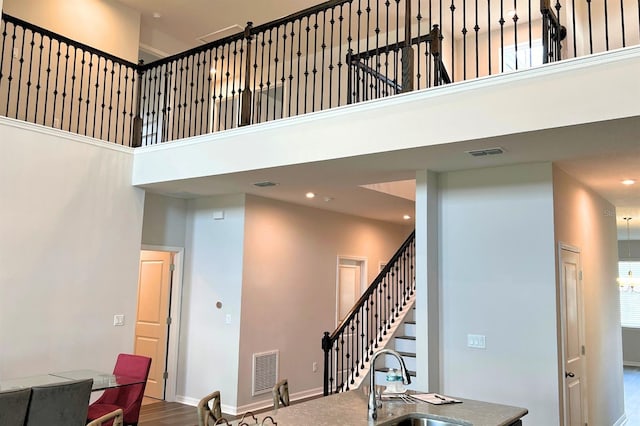 stairs featuring sink, hardwood / wood-style floors, and a high ceiling