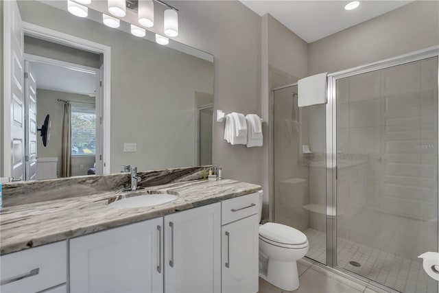 bathroom with toilet, tile flooring, a shower with shower door, and vanity