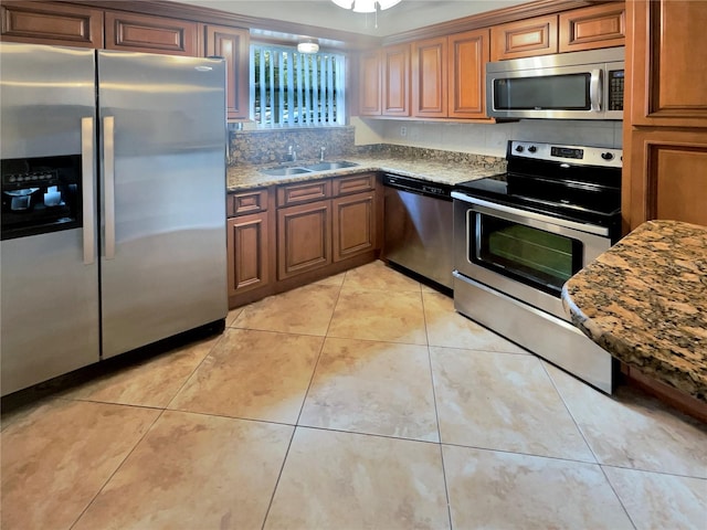 kitchen with appliances with stainless steel finishes, sink, light stone countertops, and light tile floors