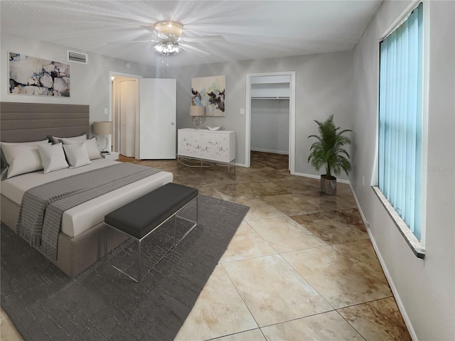 bedroom featuring a walk in closet, a closet, ceiling fan, and multiple windows