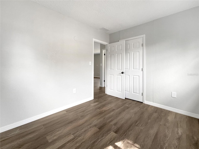 unfurnished bedroom with a closet, dark wood-type flooring, and a textured ceiling