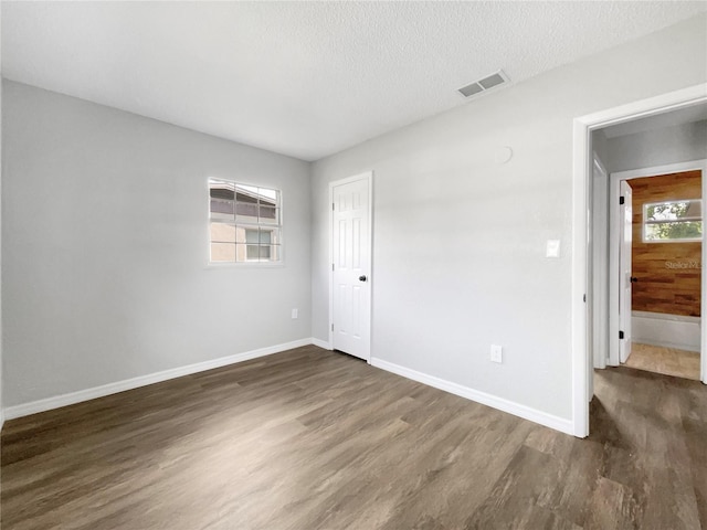 spare room with a textured ceiling and dark wood-type flooring