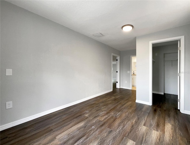 4011 Mesa Ave, Sarasota, FL 34233 - unfurnished bedroom with dark wood-type flooring, a spacious closet, baseboards, and a closet