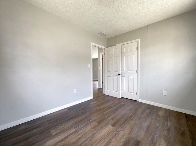 4011 Mesa Ave, Sarasota, FL 34233 - unfurnished bedroom with dark wood finished floors, baseboards, a textured ceiling, and a closet