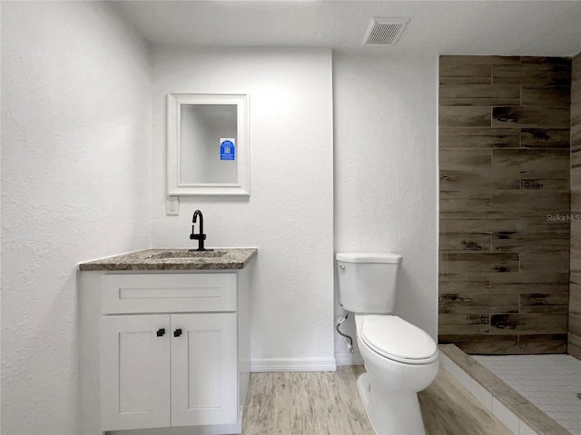 4011 Mesa Ave, Sarasota, FL 34233 - bathroom featuring vanity, toilet, tiled shower, wood finished floors, and baseboards