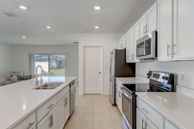 kitchen featuring white cabinets, appliances with stainless steel finishes, light tile flooring, and sink