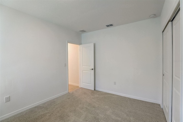 unfurnished bedroom featuring light colored carpet and a closet