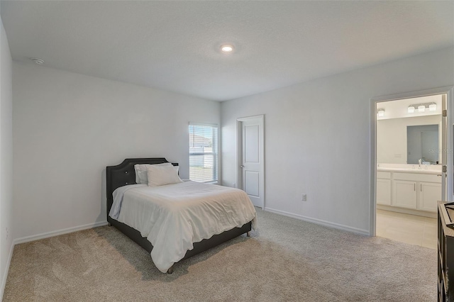 bedroom featuring light colored carpet, ensuite bathroom, and sink