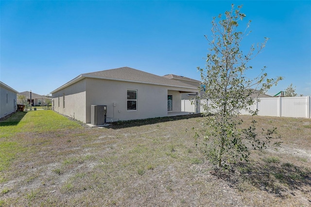 back of property with central AC unit and a yard