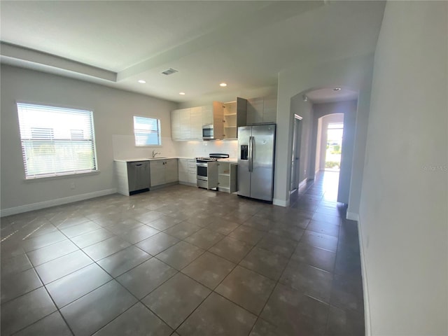 kitchen with appliances with stainless steel finishes, dark tile floors, backsplash, and sink