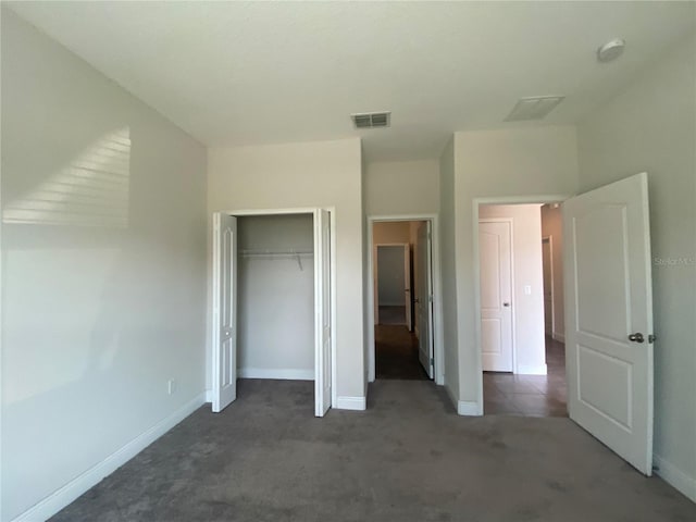 unfurnished bedroom with a closet and dark colored carpet