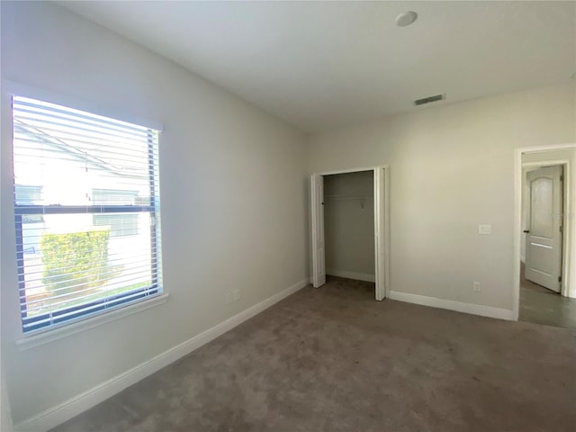 unfurnished bedroom featuring a closet and dark carpet